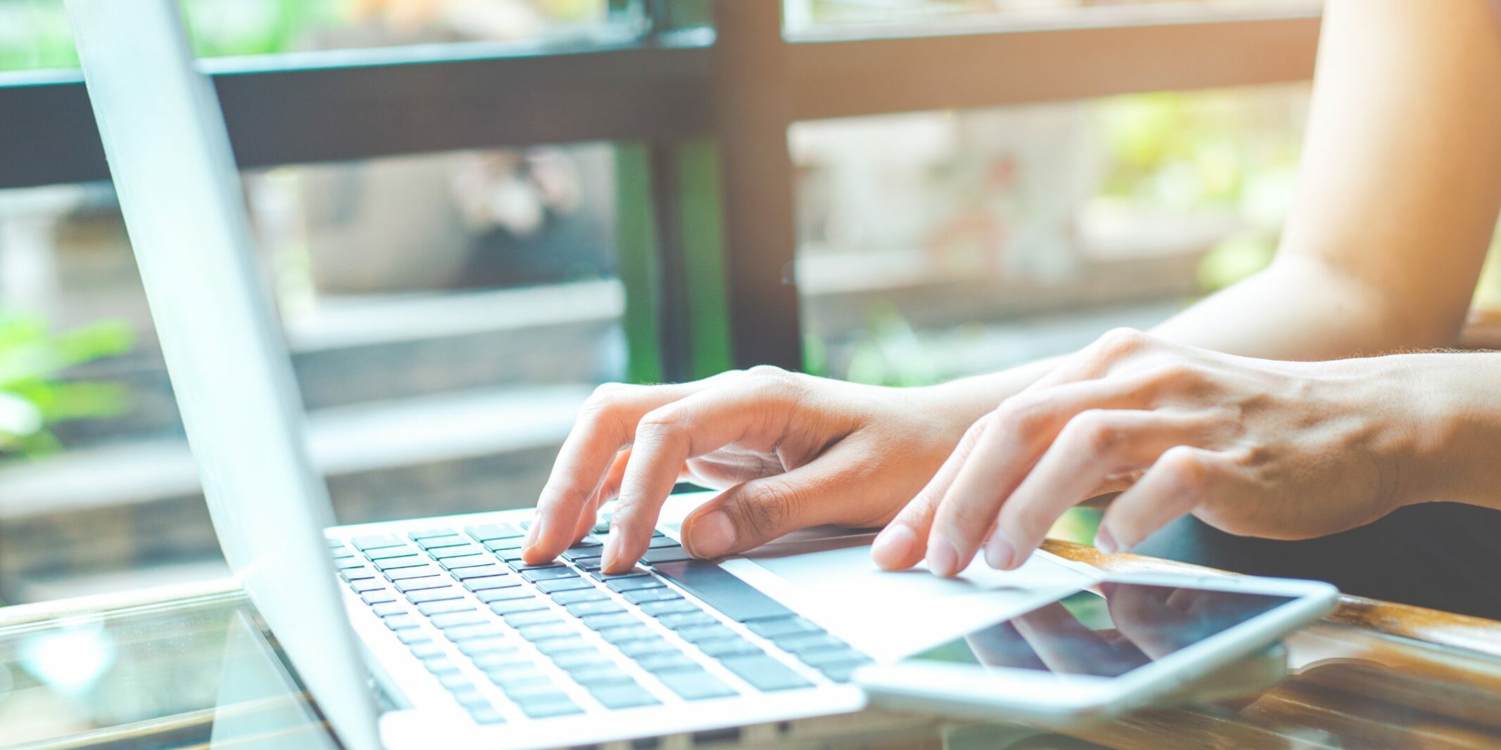 Business woman working with a laptop computer and uses a cell phone in the office.Web banner.